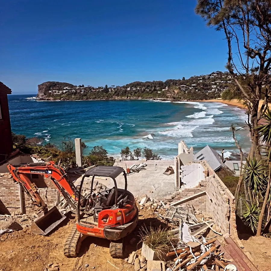 Mini excavator on a clifftop site overlooking a Northern Beaches beach
